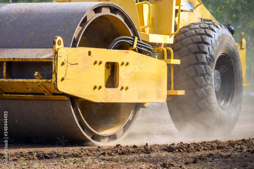 Close up of vibratory roller compactor working on construction site. Compaction machine on road construction work, earthwork. Heavy-duty machinery working on highway construction site.