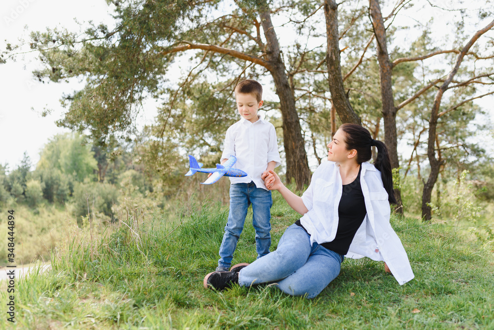 Stilish mother and handsome son having fun on the nature. Happy family concept. Beauty nature scene with family outdoor lifestyle. Happy family resting together. Happiness and harmony in family life.