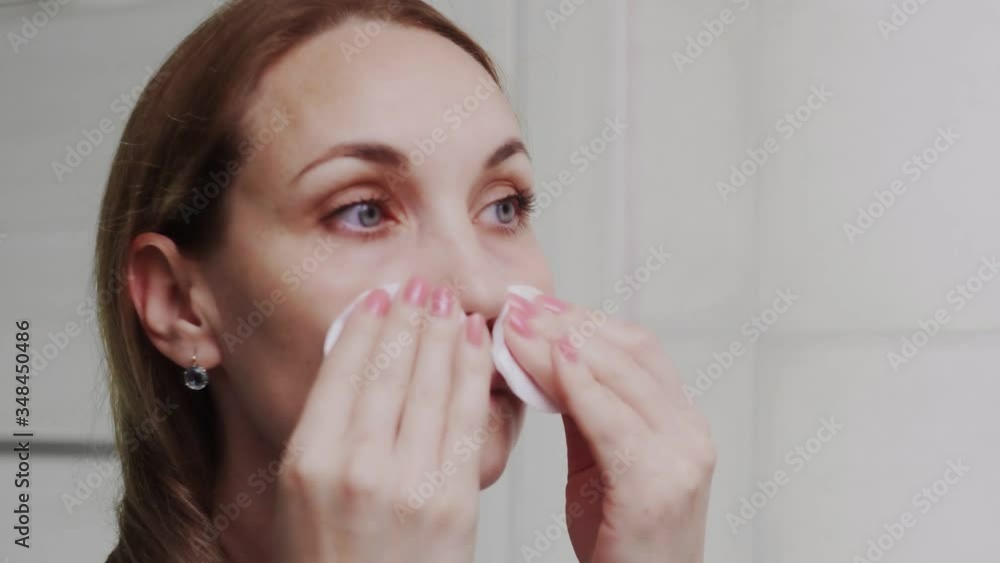 Adult woman applying lotion and looking in mirror enjoy natural beauty and healthy Adult woman applying lotion and looking in mirror enjoy natural beauty and healthy