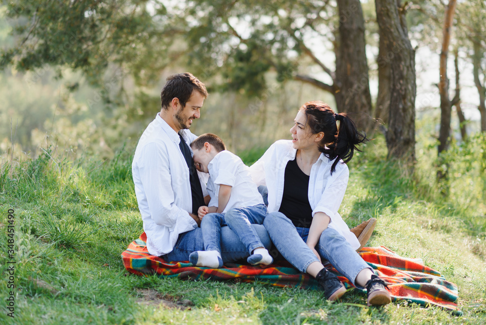 happy young family spending time outdoor on a summer day have fun at beautiful park in nature while sitting on the green grass. Happy family. happy young family spending time outdoor on a summer day have fun at beautiful park in nature while sitting on the green grass. Happy family.