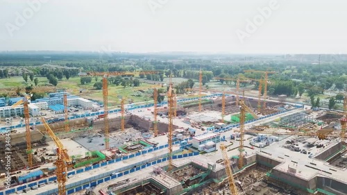 BEIJING, CHINA - Construction cranes are seen in front of new terminal of Beijing Daxing International Airport. Aerial view of the construction of hotel complexes near the airport. photo