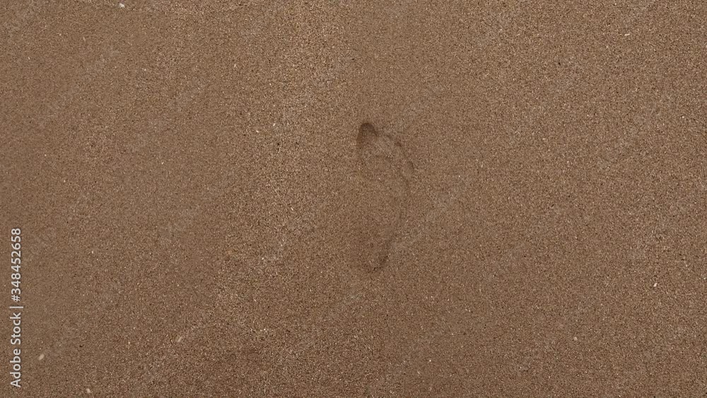 Water wave from the ocean is removing the footstep in the sand on tropical beach. Concept of romantic vacation near sea. Water wave from the ocean is removing the footstep in the sand on tropical beach. Concept of romantic vacation near sea.