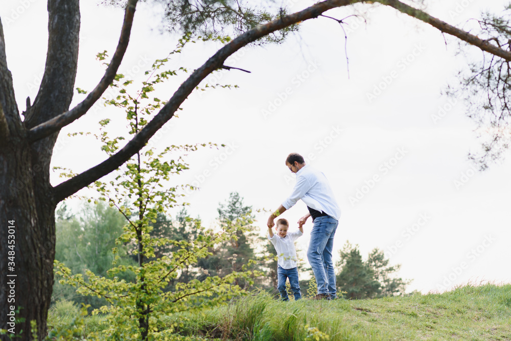 Handsome dad with his little cute son are having fun and playing on green grassy lawn. Happy family concept. Beauty nature scene with family outdoor lifestyle. family resting together. Fathers day Handsome dad with his little cute son are having fun and playing on green grassy lawn. Happy family concept. Beauty nature scene with family outdoor lifestyle. family resting together. Fathers day