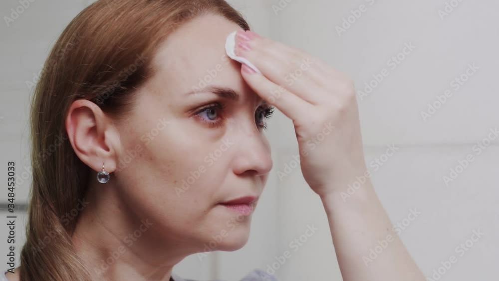 Adult woman applying lotion and looking in mirror enjoy natural beauty and healthy Adult woman applying lotion and looking in mirror enjoy natural beauty and healthy