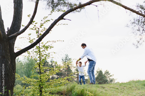 Handsome dad with his little cute son are having fun and playing on green grassy lawn. Happy family concept. Beauty nature scene with family outdoor lifestyle. family resting together. Fathers day © Serhii
