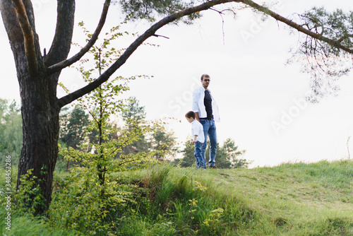 Handsome dad with his little cute son are having fun and playing on green grassy lawn. Happy family concept. Beauty nature scene with family outdoor lifestyle. family resting together. Fathers day