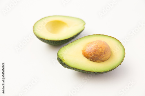 Two halves of avocado fruit with core. Closeup shot. Isolated object on white background. Fresh food or healthy diet concept