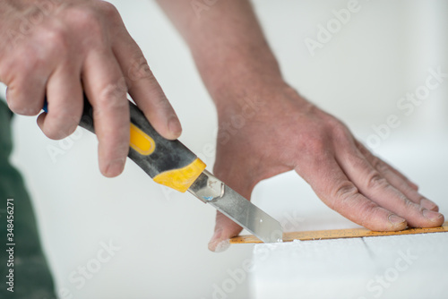 Styrofoam, seiling mounting. A man cuts foam. Warming. Repair in the house. DIY repair. Work with polystyrene foam, insulation of walls and ceiling. Male hands with line and mounting knife
