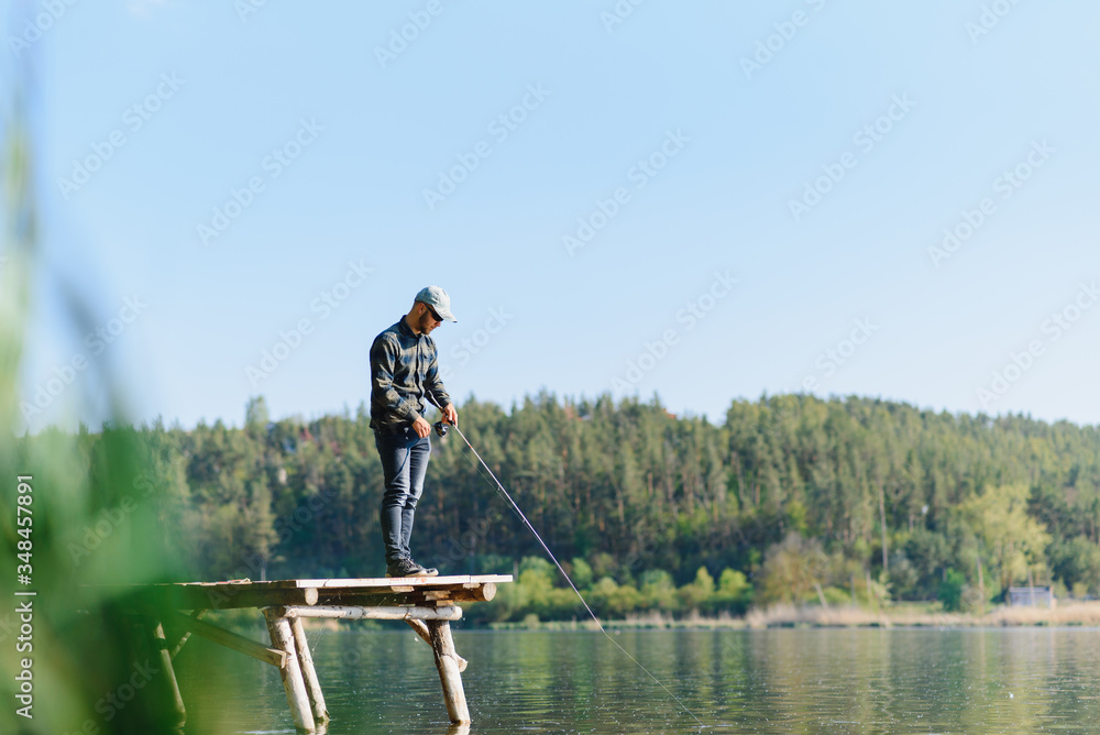 Fishing in river.A fisherman with a fishing rod on the river bank. Man fisherman catches a fish pike.Fishing, spinning reel, fish, Breg rivers. - The concept of a rural getaway. Article about fishing. Fishing in river.A fisherman with a fishing rod on the river bank. Man fisherman catches a fish pike.Fishing, spinning reel, fish, Breg rivers. - The concept of a rural getaway. Article about fishing.