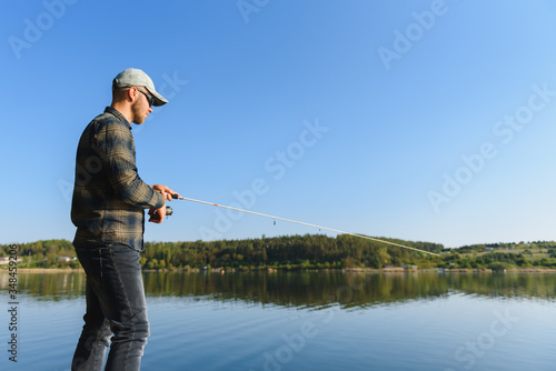 Fishing in river.A fisherman with a fishing rod on the river bank. Man fisherman catches a fish pike.Fishing, spinning reel, fish, Breg rivers. - The concept of a rural getaway. Article about fishing.