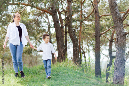 Mother and little son happy family. Attractive mom,kid boy are walking carefree outdoors summer. Parent woman goes on nature together with child,summer,spring day.Light,copy space. Happy family.