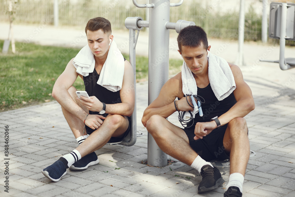 Obraz premium Men in a city. Guys in a sports clothes. Male with phone and headphones