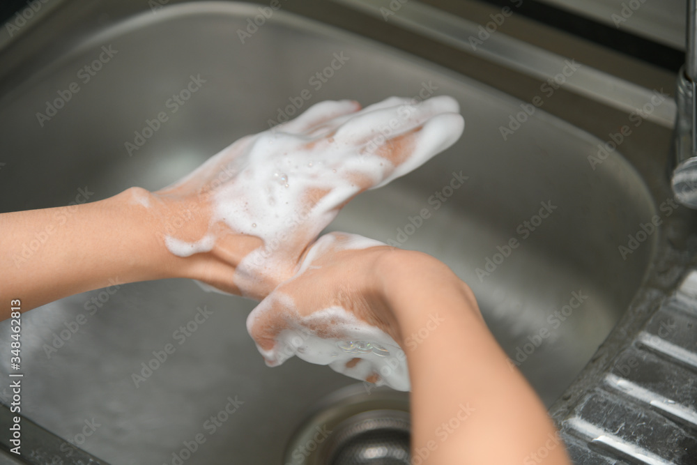 Woman washing hands in a sink with tap water