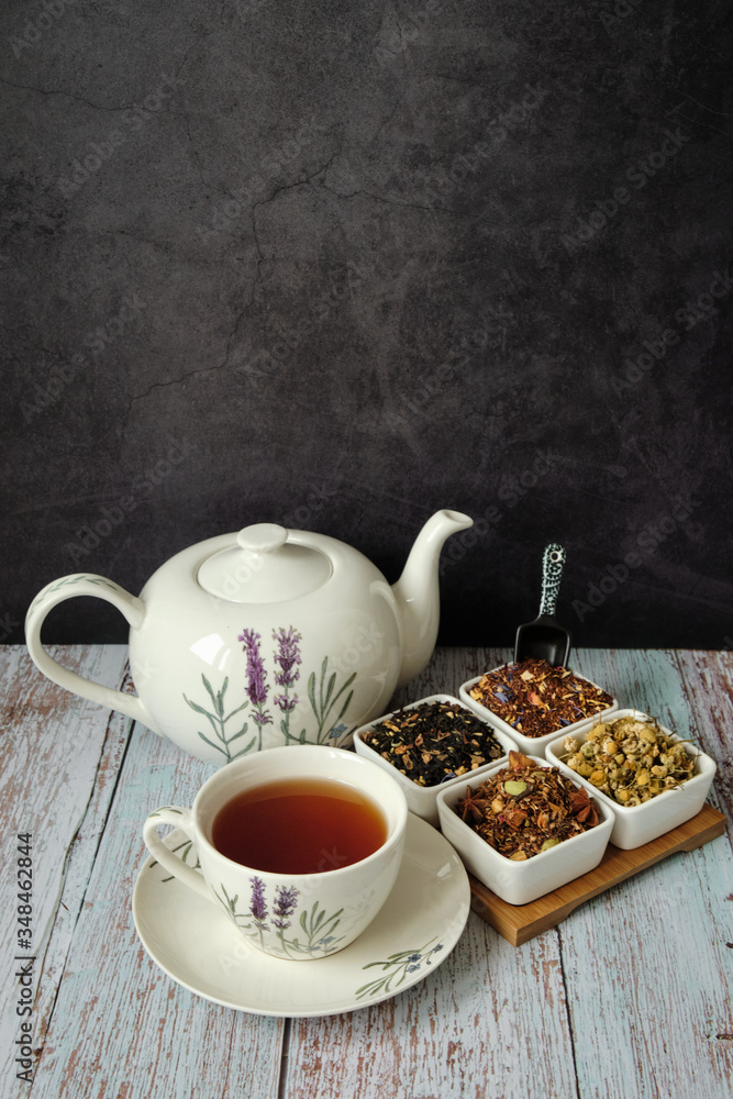 Mug with red tea, teapot and dry tea leaves. Dark background with copyspace Mug with red tea, teapot and dry tea leaves. Dark background with copyspace