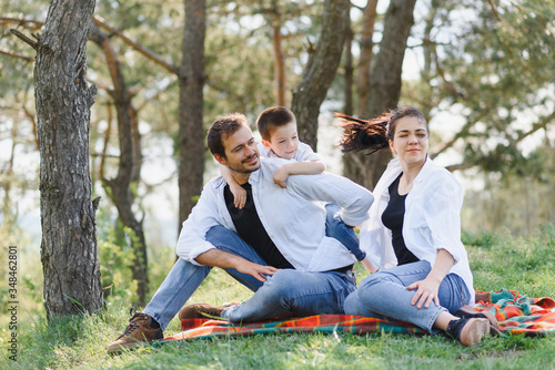 happy young family spending time outdoor on a summer day have fun at beautiful park in nature while sitting on the green grass. Happy family.