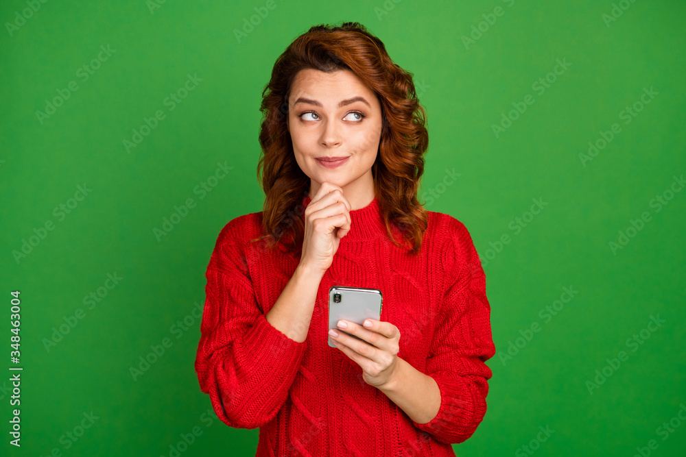Portrait of inspired interested woman use smartphone think thoughts touch chin finger decide what type wear jumper isolated over bright color background Portrait of inspired interested woman use smartphone think thoughts touch chin finger decide what type wear jumper isolated over bright color background