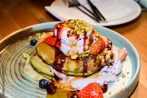 Matcha powder pancakes served in a restaurant setting, with ice cream, strawbberries and chocolate photo