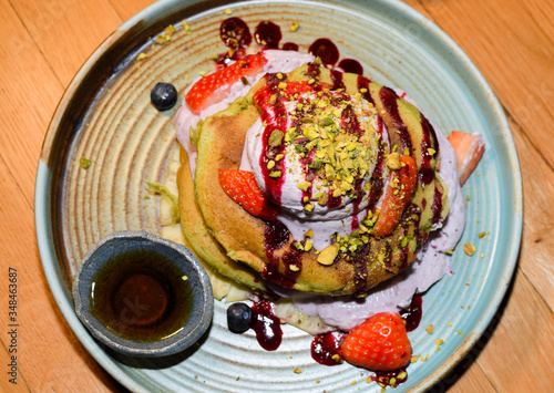 Matcha powder pancakes served in a restaurant setting, with ice cream, strawbberries and chocolate photo