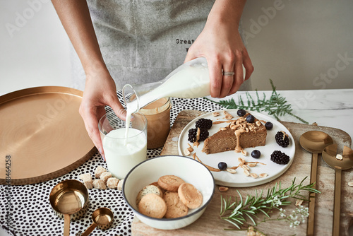 Woman pouring milk, peanut butter cake and cookies