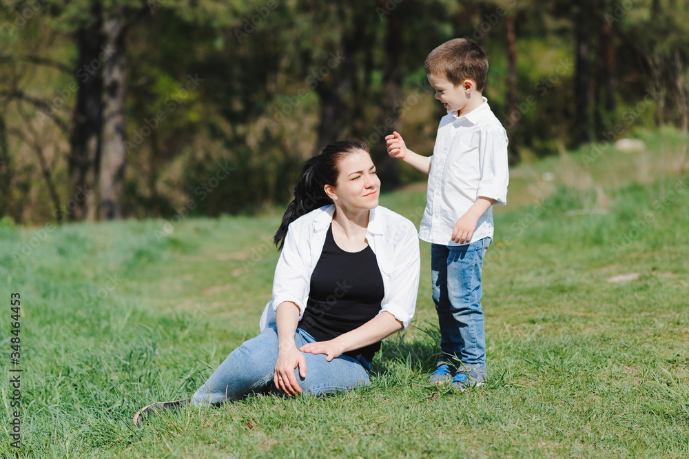 Fototapeta premium Stilish mother and handsome son having fun on the nature. Happy family concept. Beauty nature scene with family outdoor lifestyle. Happy family resting together. Happiness in family life. Mothers day.