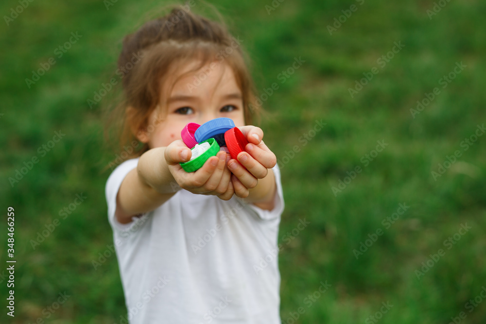A little girl holds plastic bottle caps in her hands. Volunteer charity event A little girl holds plastic bottle caps in her hands. Volunteer charity event