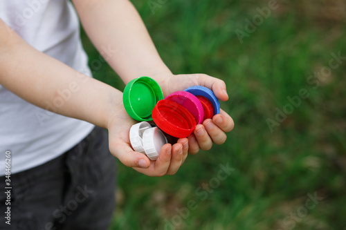 A little girl holds plastic bottle caps in her hands. Volunteer charity event "Good lids" to help orphaned children.