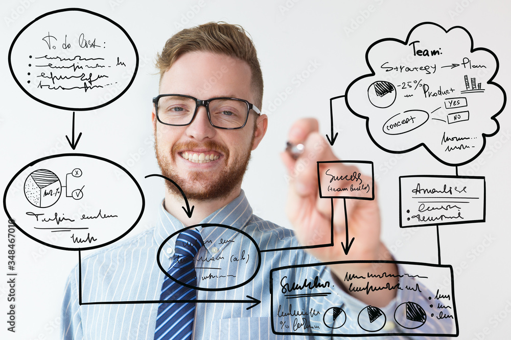 Closeup portrait of handsome young businessman writing on glass board. Businessman drawing virtual hand drawn business flowcharts. Business success or presentation concept Closeup portrait of handsome young businessman writing on glass board. Businessman drawing virtual hand drawn business flowcharts. Business success or presentation concept
