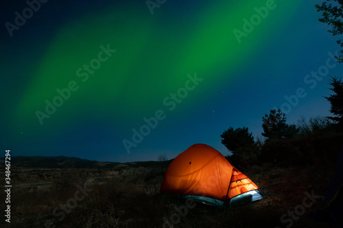 Orange tent under the night sky of the northern lights
