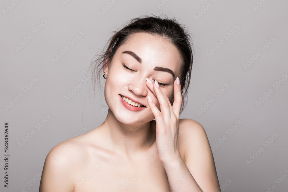 Asian woman beauty face closeup portrait. Beautiful attractive mixed race Asian female model with perfect skin isolated on gray background Asian woman beauty face closeup portrait. Beautiful attractive mixed race Asian female model with perfect skin isolated on gray background