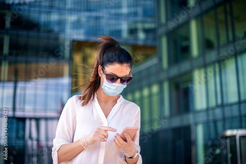 Confident woman wearing face mask for prevention and text messaging while standing outdoor