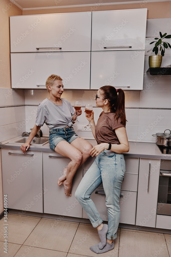 Two girls chatting with each other in the kitchen, love relationship same-sex couple girls. Family and family relationships. Two girls chatting with each other in the kitchen, love relationship same-sex couple girls. Family and family relationships.