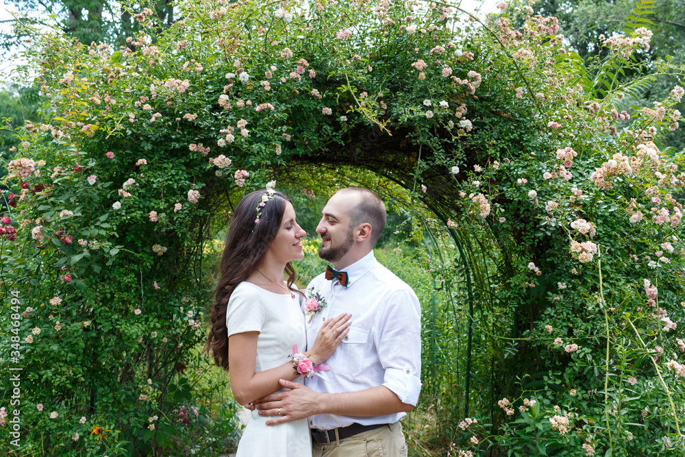 Lovers newlyweds. Beautiful couple in love. Loving couple in the garden among the flowers. Just married. Beautiful bride and groom are hugging in the park. Wedding portrait of lovers newlyweds