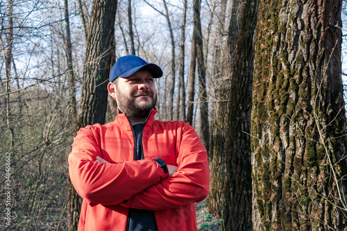A guy walking in the woods. Bearded man in the forest. Portrait of a guy in a cap among the trees. Portrait of a young bearded man in the forest.