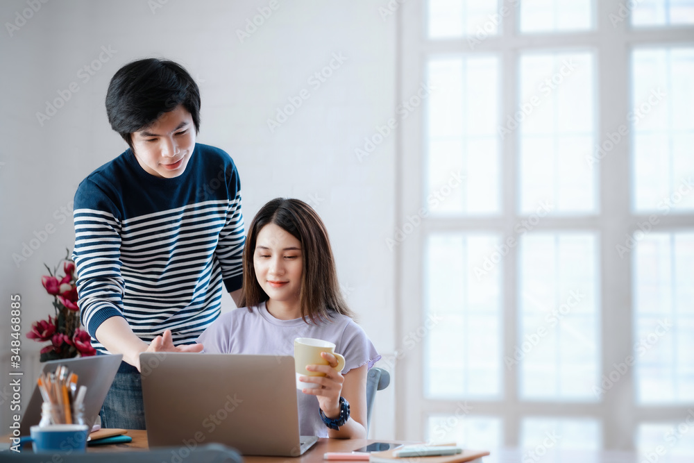 Young asian couple discussing together and typing on computer during working day in home office. Working from home concept Young asian couple discussing together and typing on computer during working day in home office. Working from home concept