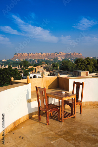 Rooftop Table with chairs with view of tourist landmark of Rajasthan - Jaisalmer Fort known as the Golden Fort Sonar quila  Jaisalmer  Rajasthan  India