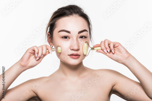 Beauty rose jade stone face roller for facial massage therapy. Portrait of Asian woman use jade aging roller isolated on white background.
