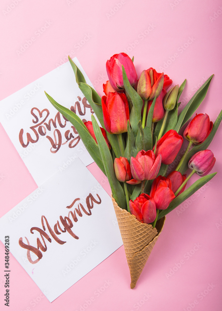 red  beautiful tulips in an ice cream waffle cone with card Womans Day on a color background. Conceptual idea of a flower gift. Spring mood