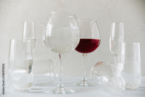 glass clear glasses with water and one glass of wine on a gray background
