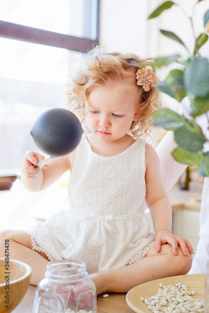 Cute little baby girl playing at home with eco-friendly wooden toys. The baby has fun with role-playing kitchen and cooking game. Cute little baby girl playing at home with eco-friendly wooden toys. The baby has fun with role-playing kitchen and cooking game.