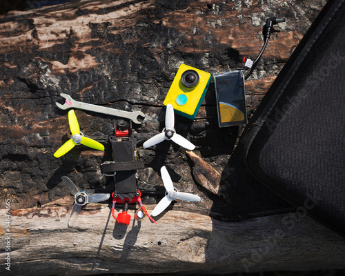 multicolored racing quadrocopter drone with tools on a log outdoors