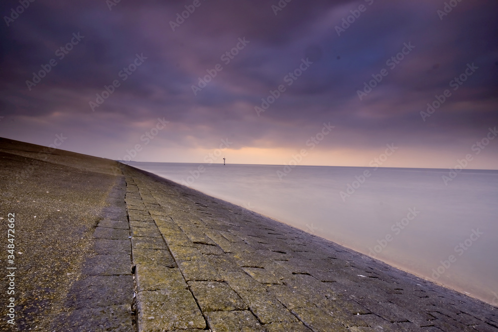 Impressive view from the dike at Moddergat, the Netherlands. Beautiful composition of stones, water and air. Sunset over the Wadden Sea. Unesco world heritage