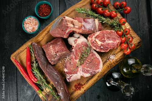 Chef prepare steak. Uncooked steak in sauce with spices an rosemary on a old wooden desk.