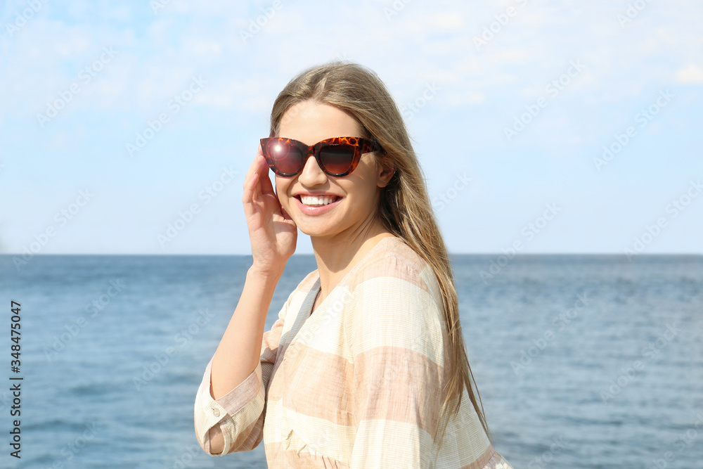 Young woman wearing stylish sunglasses near river Young woman wearing stylish sunglasses near river