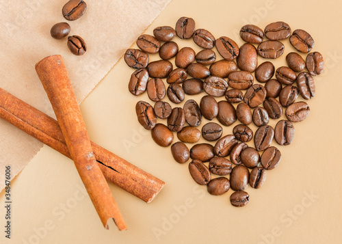 coffee beans and cinnamon sticks. Coffee beans laid out in the shape of a heart with cinnamon sticks on a beige background. Love for coffee.