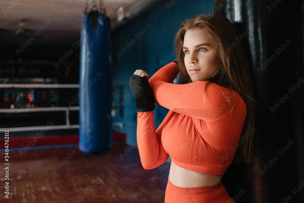Sporty girl in boxing bandages near a punching bag