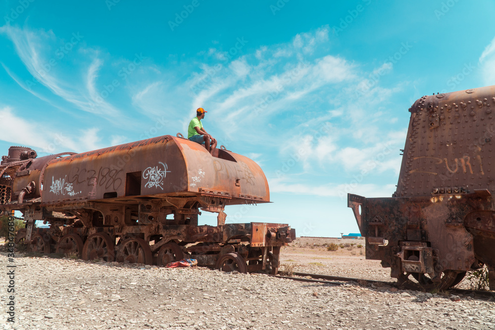 Tourist, Train Cemetry Bolivia Salt Flats. Bolivian salty desert and blue sky background. Shot in Salar de Uyuni. Rusted, waste, abandoned, locomotive graveyard, railroad concepts. Tourist attraction