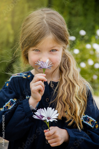 Little blonde women girl with flower surprise for mather’s day. In the garden white flower, spring or summer. smelling a flower, nose flower, flowers in hands