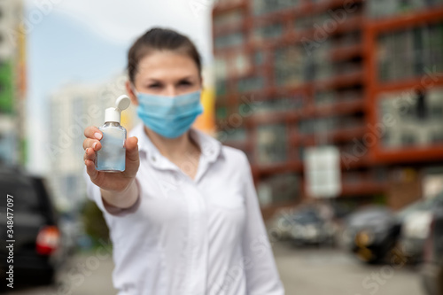 girl in a medical mask shows an antiseptic. focus on antiseptics.