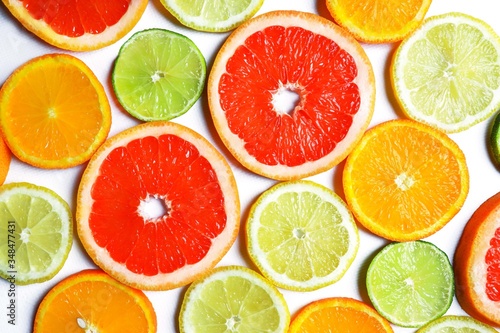 Assorted fresh juicy slices of citrus fruits: grapefruit, orange, lemon and lime. White surface, top view, flat lay.