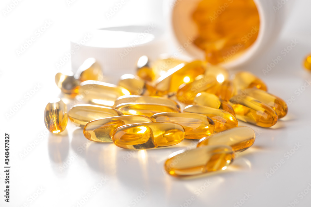 Cod liver oil capsules scattered from a bottle on white background Cod liver oil capsules scattered from a bottle on white background